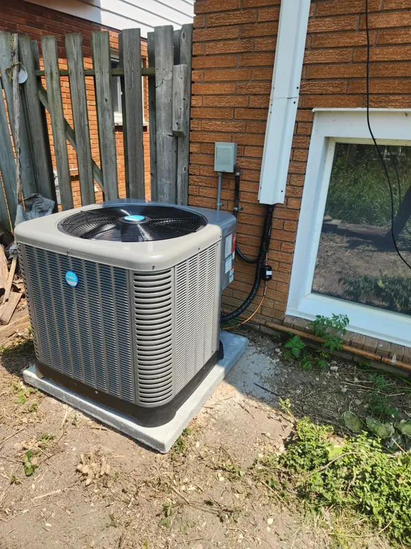 Central air conditioner set on a pad beside a home