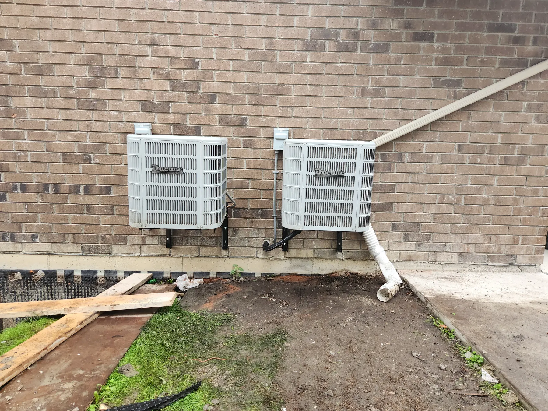 Two outdoor HVAC units mounted beside a house