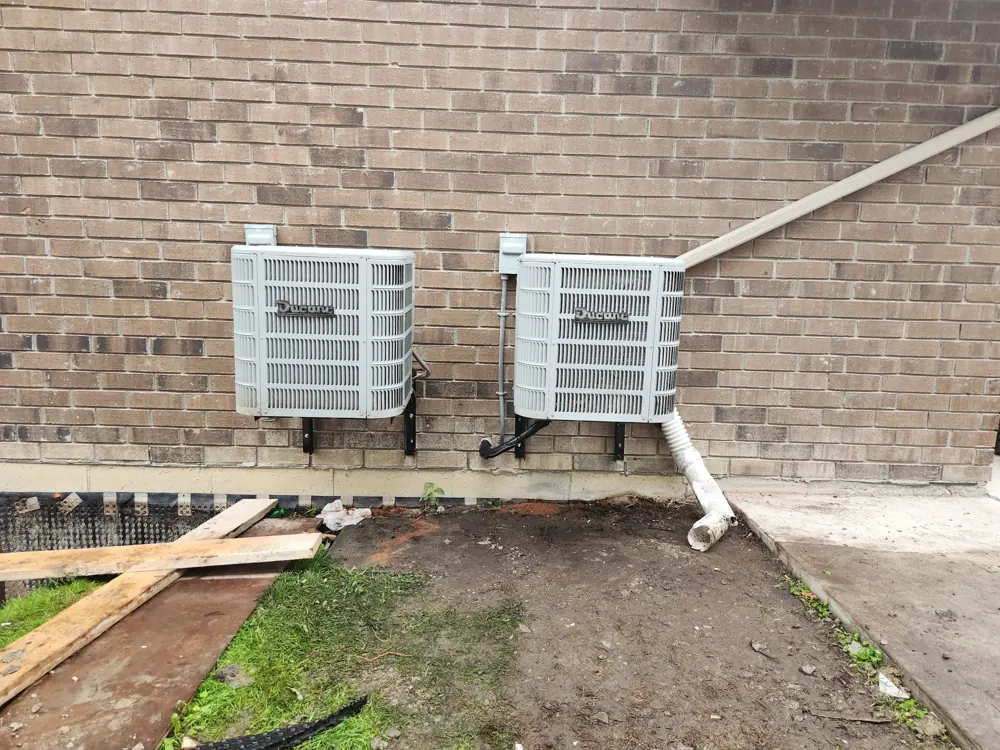 Two outdoor units mounted on a brick wall