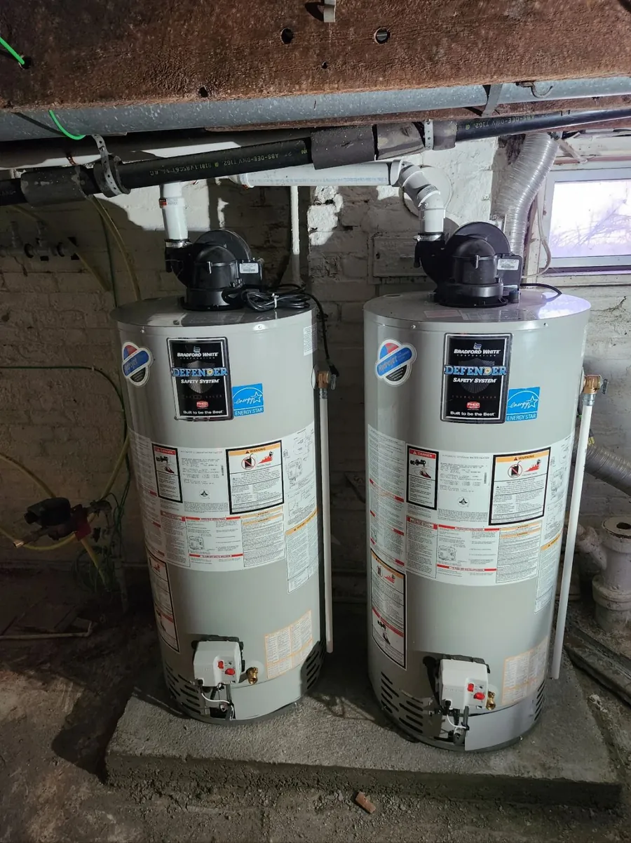 Two new gas water heaters on a level cement pad